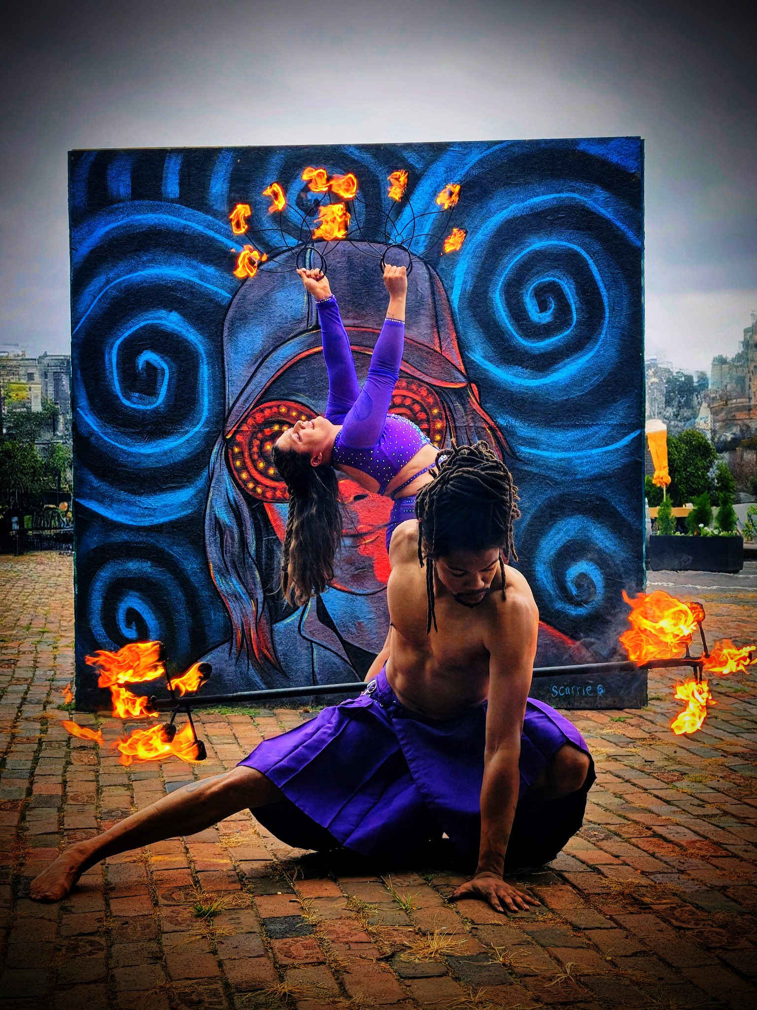 Nick May two-performer fire show with female performer and mural backdrop