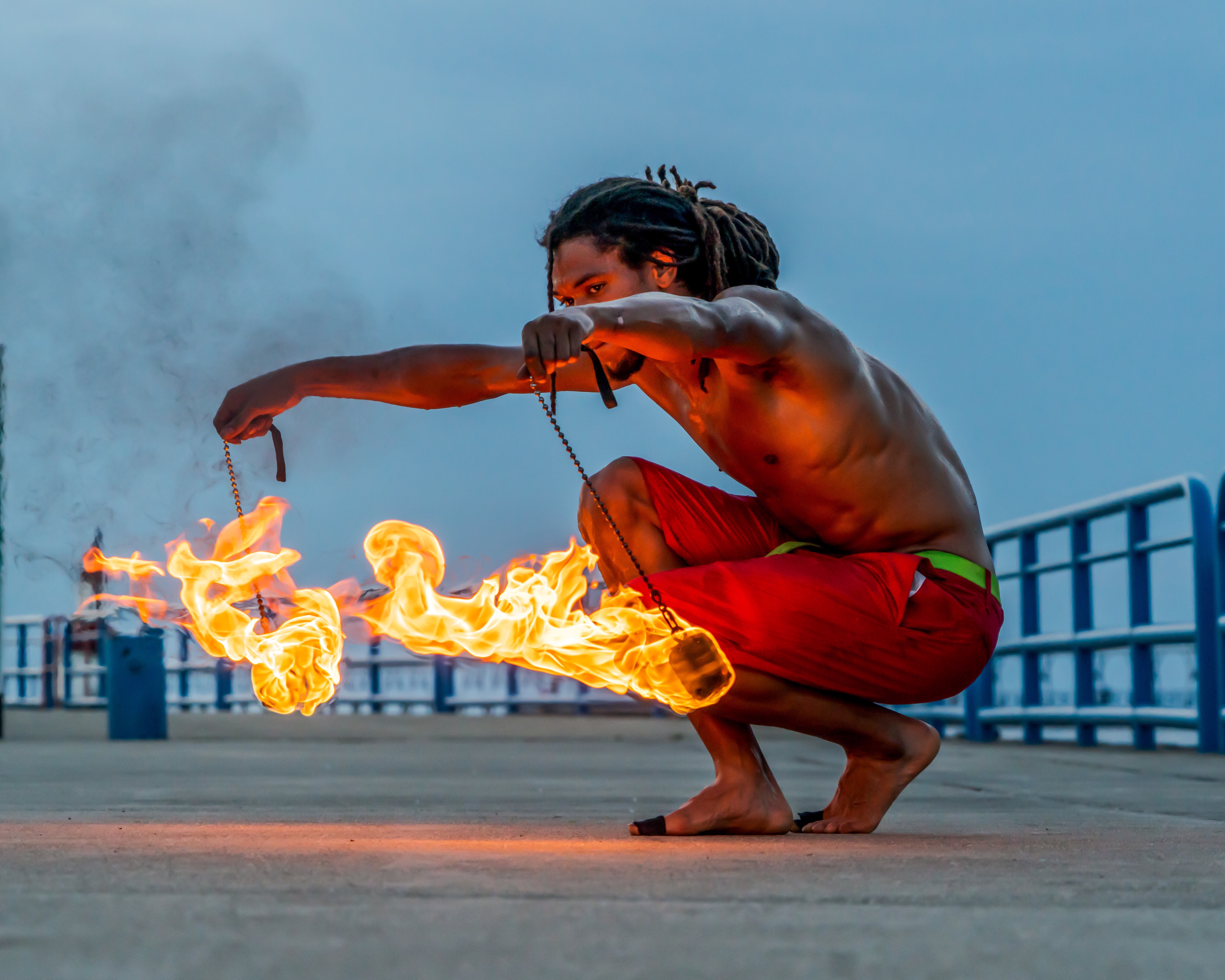 Nick May crouching with fire poi horizontal drag